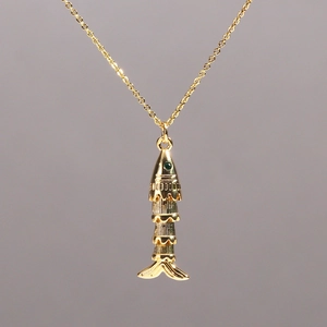 Detailed macro view of a golden koi fish pendant featuring green gemstone eyes and scales