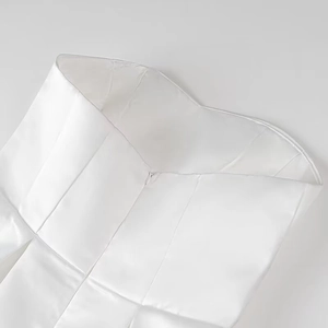 Dettaglio dell'elegante abito corto a fascia in raso bianco con cuciture strutturali lucide