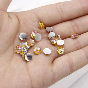 Macro shot of 6mm yellow scale resin cabochon held in hand for DIY jewelry making