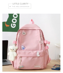 Dettaglio dello zaino scolastico rosa con spille di cartoni animati e ciondolo a orsetto