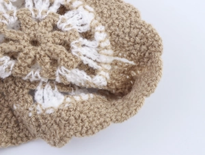 Close-up of khaki and white crochet knit fabric showing intricate hollow-out texture