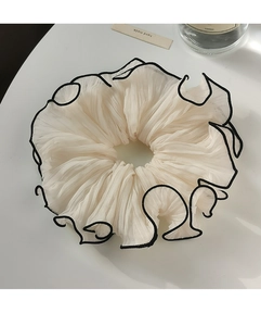 Close-up of pleated cream scrunchie with black trim detail and handmade label