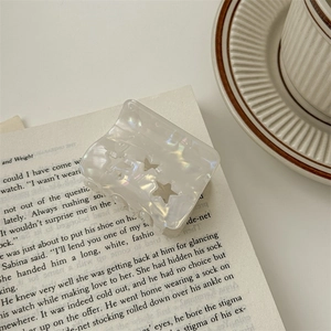 Macro detail of pearlescent hair claw with star cutouts on an open vintage book page