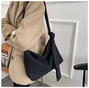 Detail of the black minimalist crossbody bag featuring a unique knotted shoulder strap design