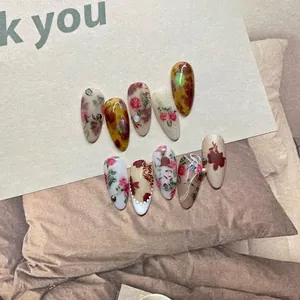 Vintage floral press-on nails with amber texture, pearls and matte finish on aesthetic background