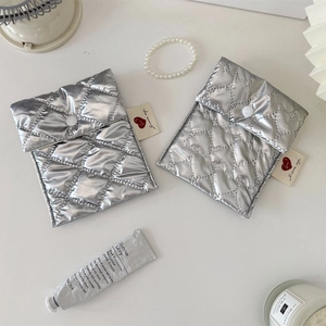 Detail of silver quilted heart sanitary bag with metallic finish and button closure