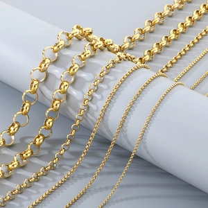 Close-up of various gold-tone stainless steel pearl and cable chains on grey pedestals