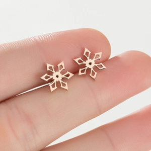 Macro shot of rose gold snowflake earrings on a finger showing detail and real scale