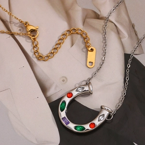 Close-up of U-shaped horseshoe pendant with red green purple gems on silver necklace