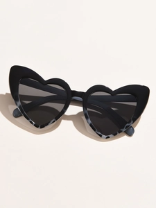 Detail of glossy black heart-shaped cat-eye sunglasses with dark lenses on beige base