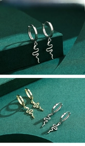 Détail macro des boucles d'oreilles serpent en argent S925 montrant le poinçon et le métal