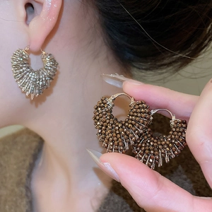 Close-up of vintage beaded hoop earrings with bronze crystals and gold-tone metal frame