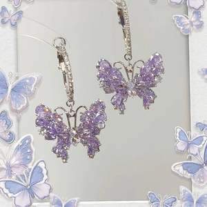 Macro detail of purple butterfly earrings with silver hoop and sparkling cubic zirconia
