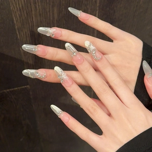 Détail de faux ongles en amande avec papillons argentés et strass brillants décoratifs