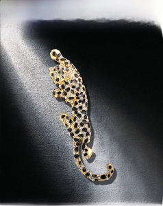 Macro shot of luxury leopard brooch with gold plating, sparkling rhinestones and green eyes