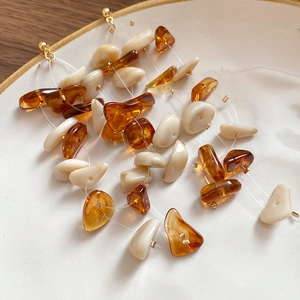 Detail of amber and cream resin beaded earrings displayed on a white ceramic tray