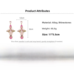 Detail view of gold vintage cross earrings with pink rhinestones and silver needles