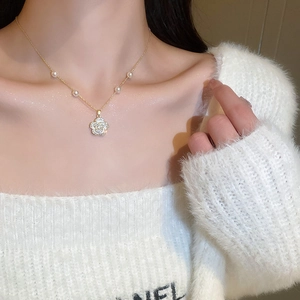 Detailed view of camellia flower necklace with gold chain and pearls on a collarbone