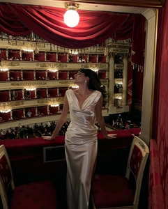 Elegante abito da sera in raso bianco con scollo a cappuccio e spacco in un teatro di lusso