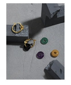 Macro view of S925 silver knot design earrings paired with vibrant round gemstone-like rings.