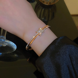 Detailed close-up of rose gold bangle with micro-paved diamonds and geometric buckle