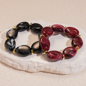 Detail view of marble pattern acrylic oval beads with golden spacers on stone
