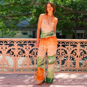 Detail of summer two-piece set with orange landscape print and wide-leg trousers