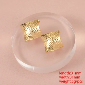 Macro view of gold square hammered stud earrings measuring 31mm on a display stand