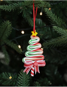 Christmas tree shaped candy ornament with red bow hanging on a festive green pine branch