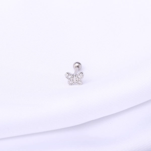 Macro shot of silver butterfly tragus stud with clear crystals on white fabric