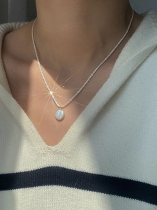 Close-up of S925 silver necklace with baroque pearl pendant worn by a model