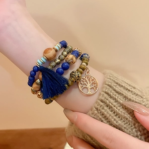 Detail of bohemian multilayer sandalwood beaded bracelet with tree of life charm and blue tassel