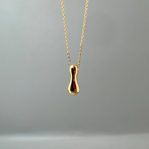 Detail of a polished gold teardrop pendant on a fine link chain with metallic luster