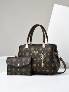Brown monogram tote bag set with gold hardware and charm on white geometric background