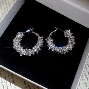 Macro shot of sparkling silver hoop earrings with baguette cubic zirconia in a jewelry box