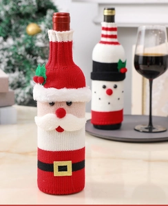 Close-up of knitted Santa Claus and snowman wine bottle covers on a festive dinner table