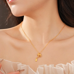 Detailed view of a gold-plated necklace with a rocking horse and rectangular pendant