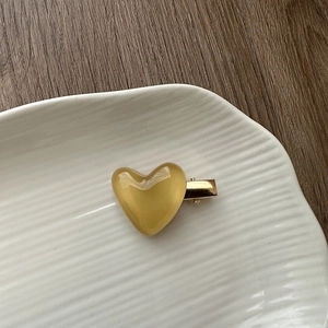Detail of amber heart resin hair clip with gold metal clasp on ceramic plate