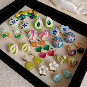 Detailed overhead view of vintage colorful enamel heart and flower earrings on black velvet