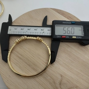 Close-up measurement of 56.0mm inner diameter for gold clover zircon bangle with a caliper