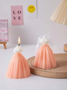 Close-up of a lit wedding dress scented candle with orange pleated skirt details