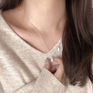 Close-up of a 925 sterling silver bear pendant necklace on a beige sweater