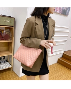 Lifestyle shot of pink quilted shoulder bag with gold chain strap on a wooden staircase