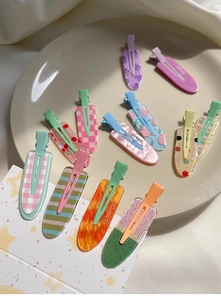 Flat lay of colorful acrylic hair clips with fruit patterns on a beige plate