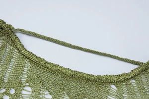 Close-up of green knit fabric texture showing breathable crochet pattern on dress