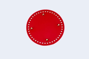 Macro detail of red leather circular bag base with gold metal feet for DIY crochet projects