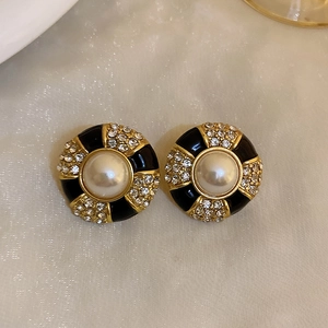 Macro shot of vintage round black and gold earrings with pearl and crystal detail