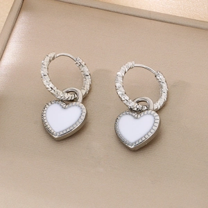 Détail des pendentifs cœur en émail blanc avec boucles d'oreilles créoles torsadées argent