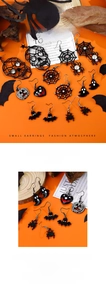 Detalle macro de pendientes de Halloween con motivos de araña, fantasma y calabaza sobre fondo naranja