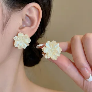 Elegant white camellia flower stud earrings with a pearl finish on model for women